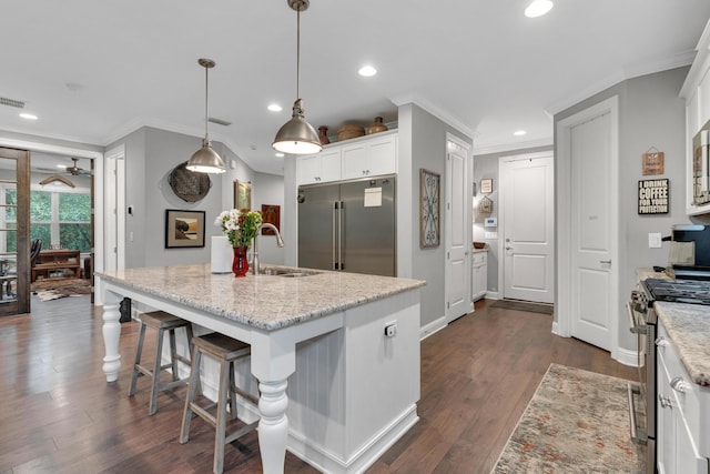 kitchen with white cabinetry, hanging light fixtures, an island with sink, and stainless steel appliances