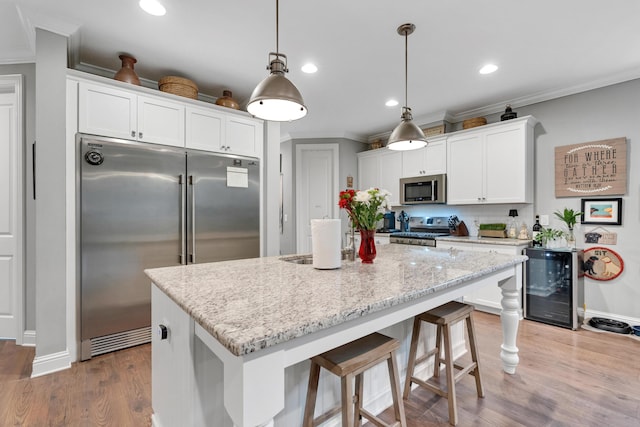 kitchen with white cabinets, hanging light fixtures, stainless steel appliances, and wine cooler