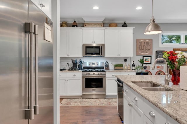 kitchen with white cabinets, hanging light fixtures, sink, and appliances with stainless steel finishes