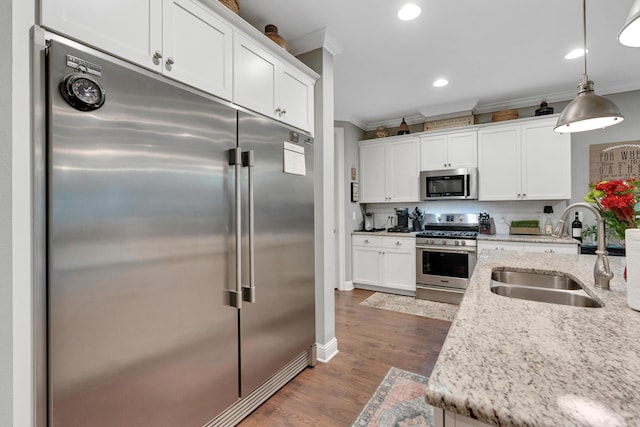 kitchen with white cabinets, sink, decorative light fixtures, light stone counters, and stainless steel appliances