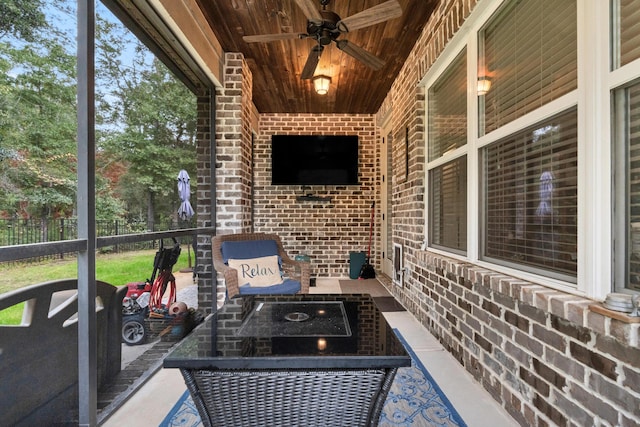 unfurnished sunroom with ceiling fan, a healthy amount of sunlight, and wood ceiling