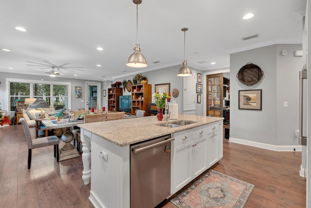 kitchen featuring stainless steel dishwasher, sink, white cabinetry, hanging light fixtures, and an island with sink