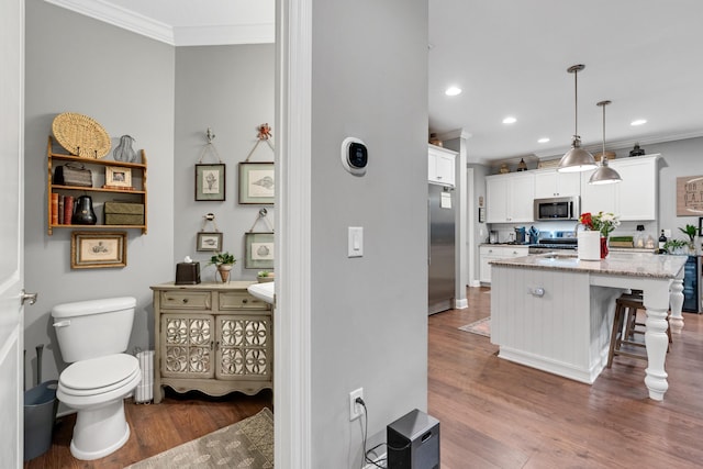 bathroom featuring hardwood / wood-style flooring, toilet, and crown molding