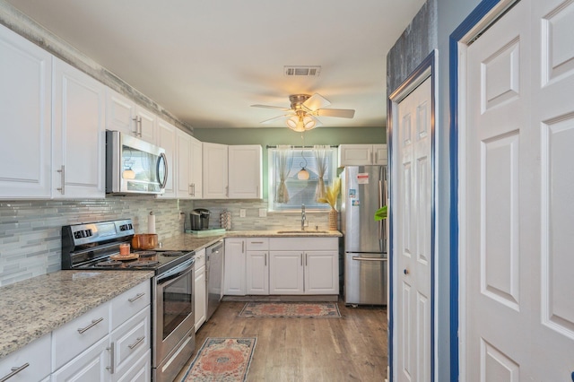 kitchen featuring white cabinetry, sink, ceiling fan, stainless steel appliances, and light wood-type flooring