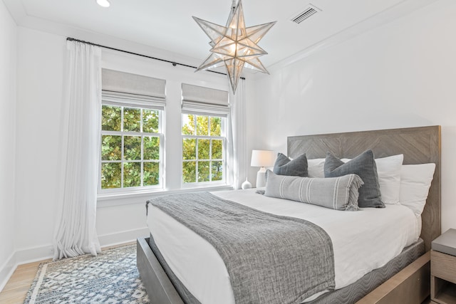 bedroom with ornamental molding, a notable chandelier, and hardwood / wood-style flooring