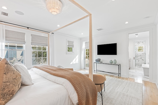 bedroom featuring a notable chandelier, light hardwood / wood-style floors, crown molding, and connected bathroom