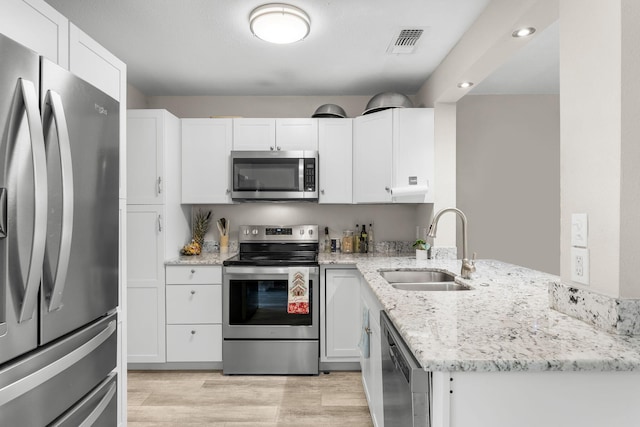 kitchen with light stone counters, sink, white cabinets, and stainless steel appliances