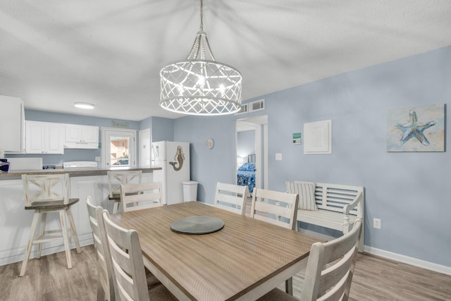 dining area featuring light hardwood / wood-style flooring and a textured ceiling