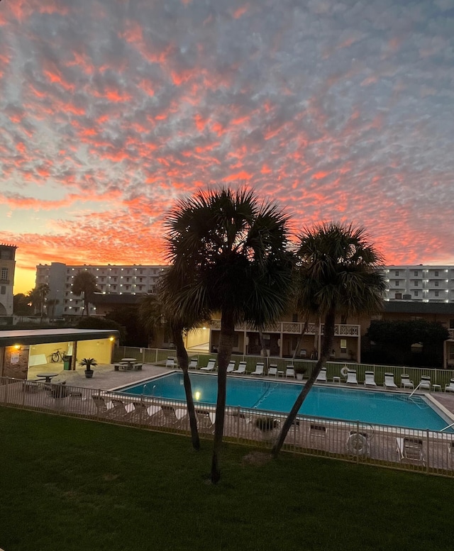 pool at dusk with a yard and a patio