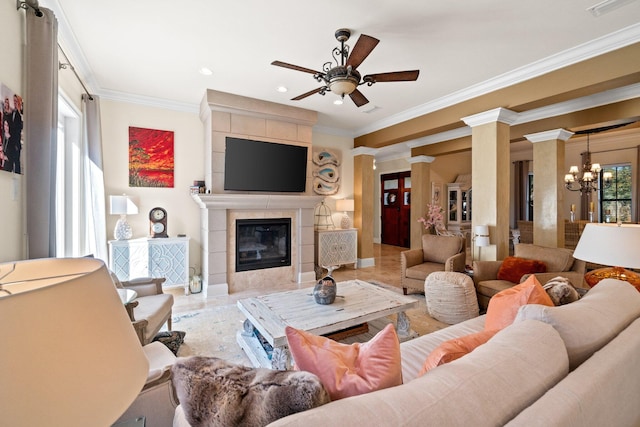 living room with ceiling fan with notable chandelier, crown molding, a fireplace, and decorative columns