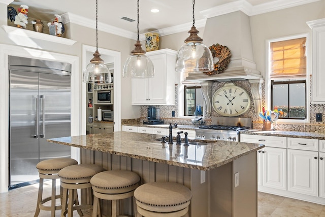 kitchen with white cabinetry, stone counters, built in appliances, decorative backsplash, and custom range hood