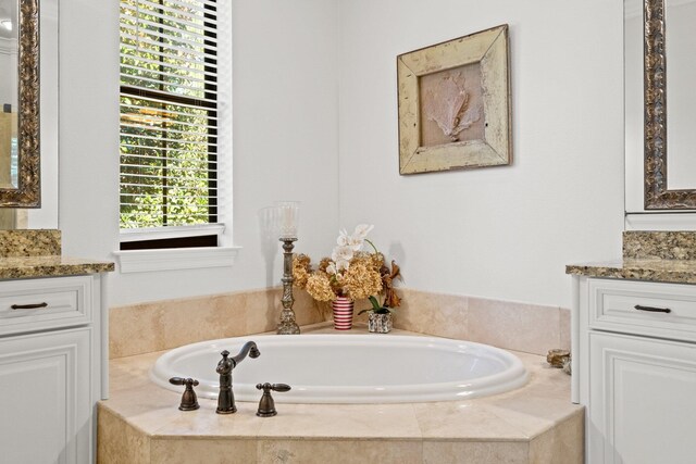 bathroom with tiled tub and vanity