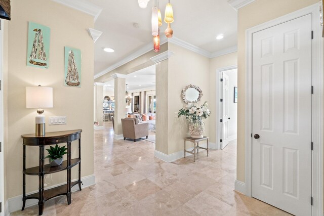 hallway with a chandelier, decorative columns, and ornamental molding