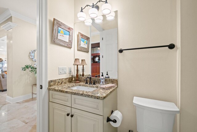 bathroom with toilet, vanity, and ornamental molding