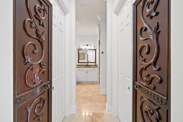 hall with light tile patterned floors and ornamental molding