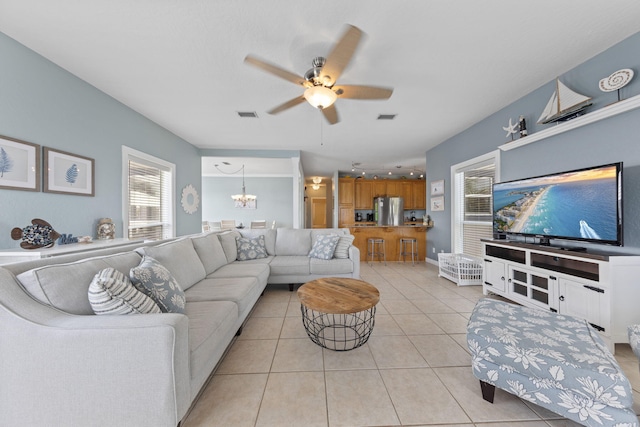 living room featuring light tile patterned floors and ceiling fan with notable chandelier