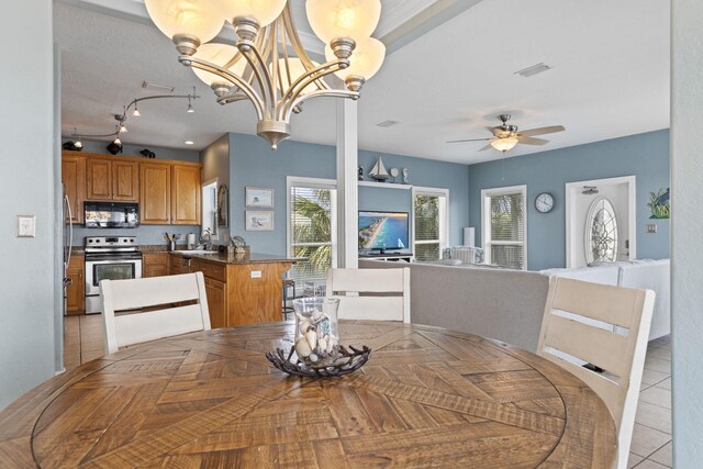 dining area featuring sink, light tile patterned floors, and ceiling fan with notable chandelier