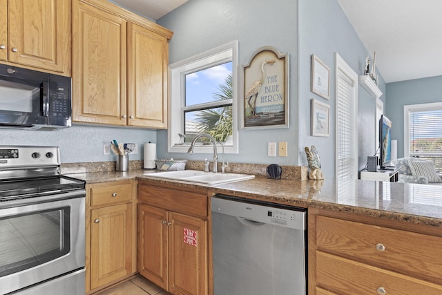 kitchen with light tile patterned floors, light stone countertops, sink, and appliances with stainless steel finishes