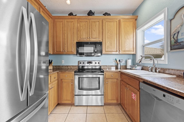 kitchen with light tile patterned floors, a textured ceiling, stainless steel appliances, and sink