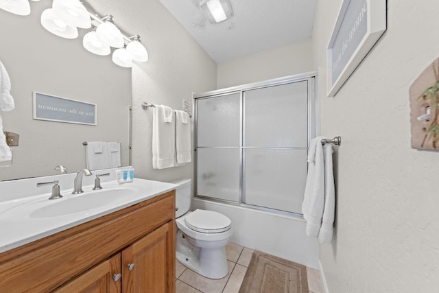 full bathroom with vanity, tile patterned floors, bath / shower combo with glass door, toilet, and a textured ceiling