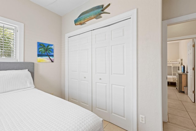 bedroom with light tile patterned floors, a closet, and ceiling fan