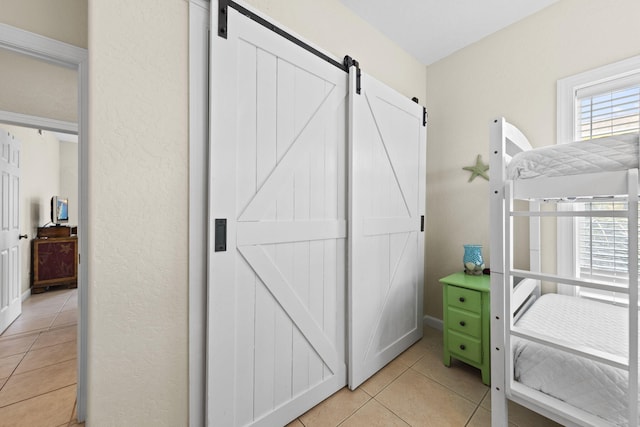 bedroom with a barn door and light tile patterned floors