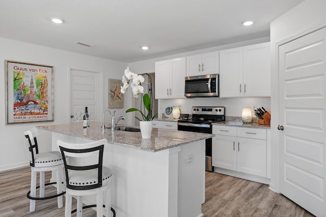 kitchen with a kitchen island with sink, white cabinets, and appliances with stainless steel finishes