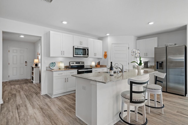 kitchen with sink, light hardwood / wood-style flooring, an island with sink, white cabinetry, and stainless steel appliances