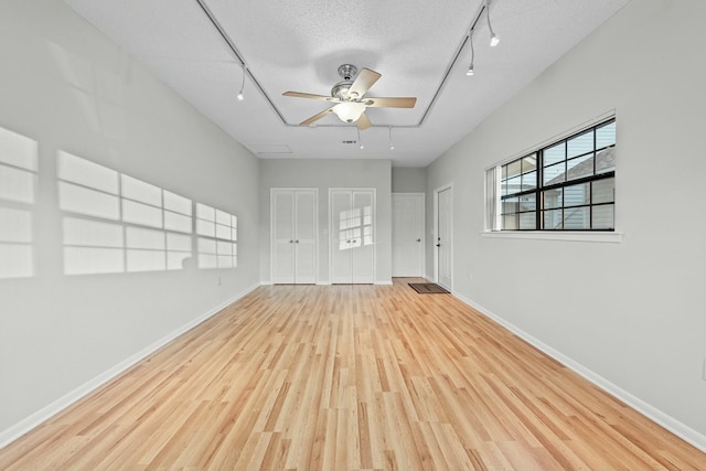 spare room featuring track lighting, a textured ceiling, and light wood-type flooring