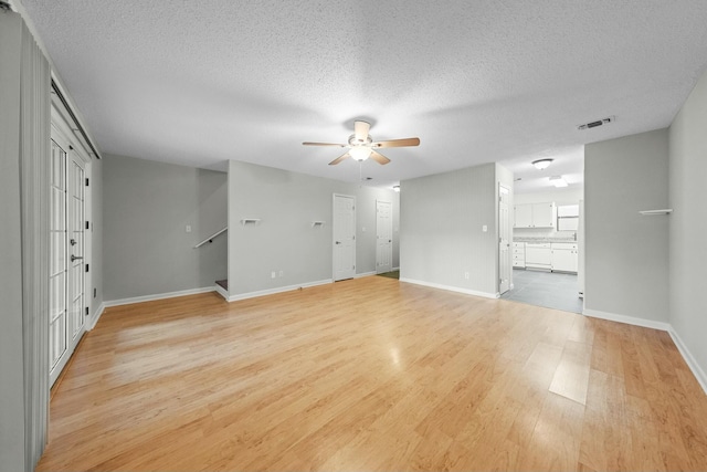 unfurnished living room featuring a textured ceiling, light wood-type flooring, and ceiling fan