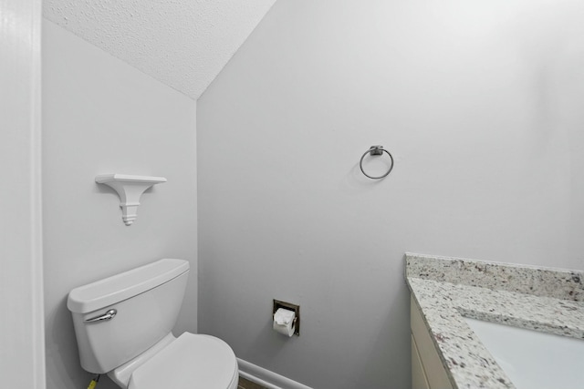 bathroom with vanity, toilet, lofted ceiling, and a textured ceiling