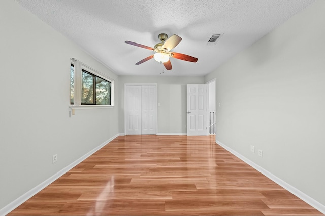 unfurnished bedroom with a closet, ceiling fan, light hardwood / wood-style flooring, and a textured ceiling