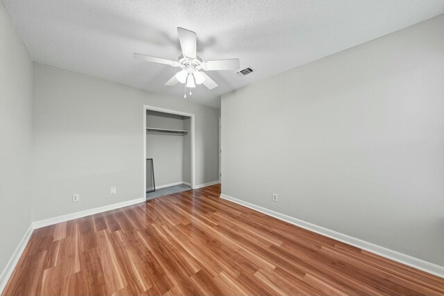 unfurnished bedroom with ceiling fan, a closet, a textured ceiling, and light wood-type flooring