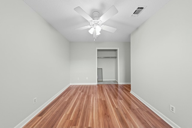 unfurnished bedroom with ceiling fan, light wood-type flooring, a textured ceiling, and a closet