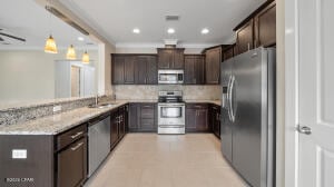 kitchen with dark brown cabinetry, decorative backsplash, recessed lighting, light tile patterned flooring, and stainless steel appliances