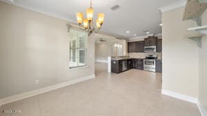 kitchen with stainless steel appliances, dark brown cabinetry, an inviting chandelier, and ornamental molding