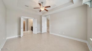 unfurnished room with baseboards, a tray ceiling, and a ceiling fan