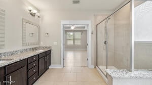 full bath with double vanity, baseboards, a stall shower, and tile patterned flooring