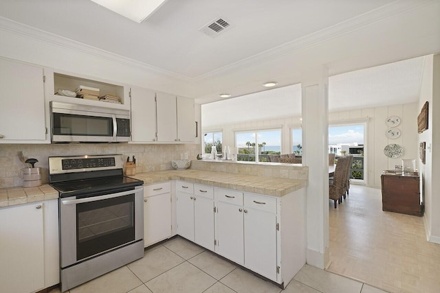 kitchen with white cabinets, tasteful backsplash, appliances with stainless steel finishes, and tile countertops