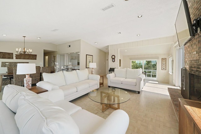 living room featuring a brick fireplace, vaulted ceiling, an inviting chandelier, and light parquet flooring