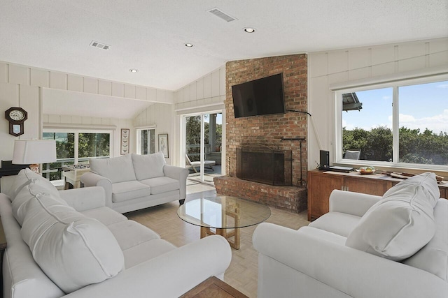 living room featuring a fireplace, a textured ceiling, plenty of natural light, and lofted ceiling