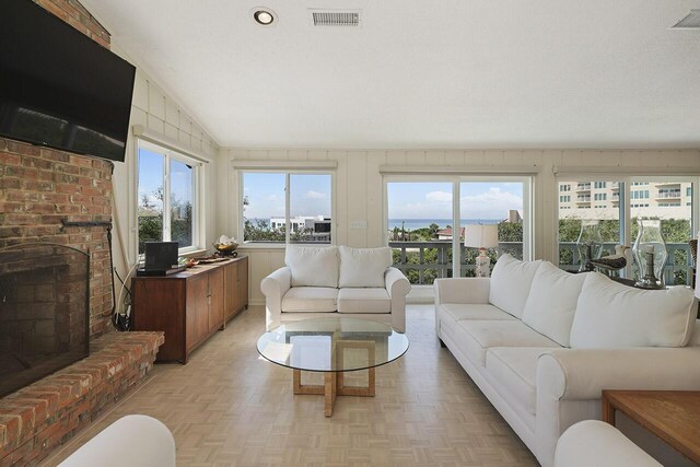 living room featuring a brick fireplace, light parquet flooring, and vaulted ceiling