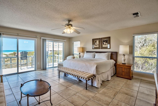 bedroom featuring ceiling fan, access to exterior, a textured ceiling, and multiple windows