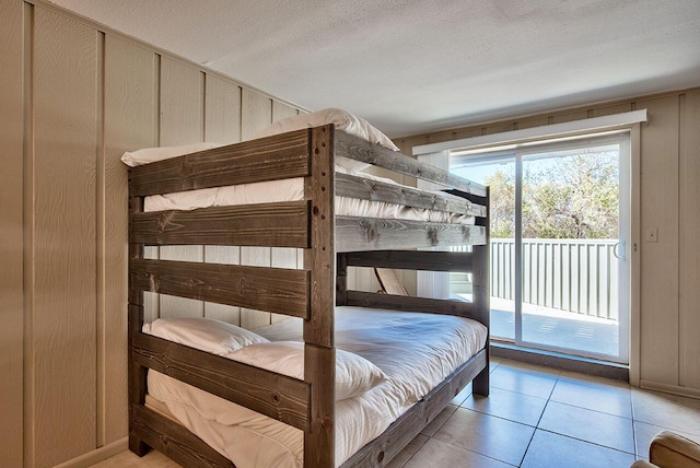 bedroom featuring access to outside, light tile patterned floors, and a textured ceiling