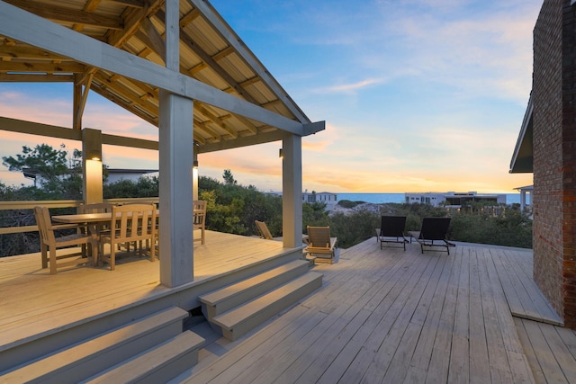 deck at dusk with a gazebo and a water view