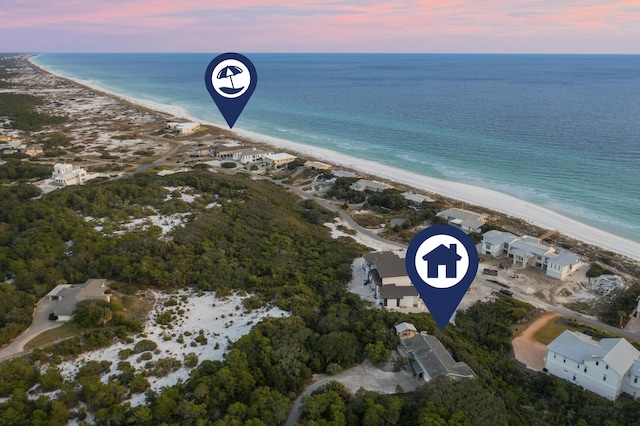 aerial view at dusk featuring a beach view and a water view