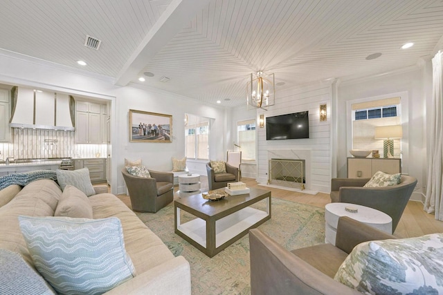 living room with a fireplace, light hardwood / wood-style flooring, wooden ceiling, and ornamental molding