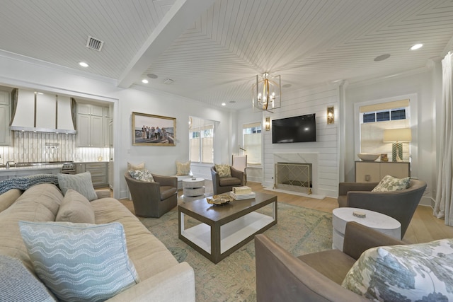 living room with a large fireplace, light hardwood / wood-style flooring, ornamental molding, and wood ceiling