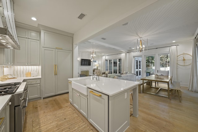 kitchen featuring a breakfast bar, ventilation hood, sink, a kitchen island, and light hardwood / wood-style floors