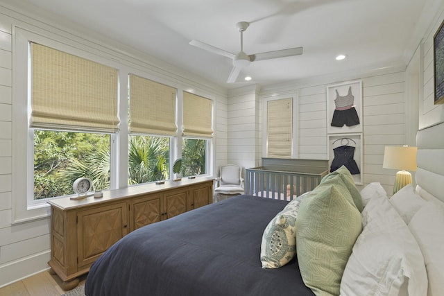 bedroom featuring ceiling fan, wood walls, and light wood-type flooring